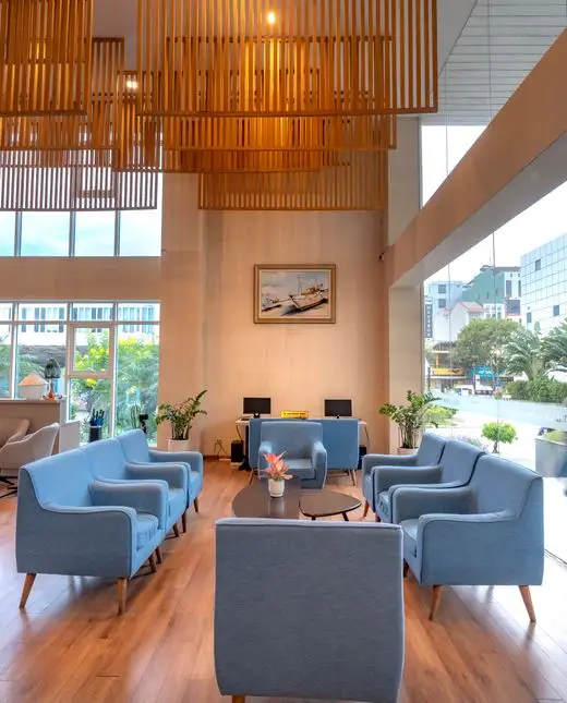 The lobby of a hotel, with armchairs arranged around low tables under a timber ceiling